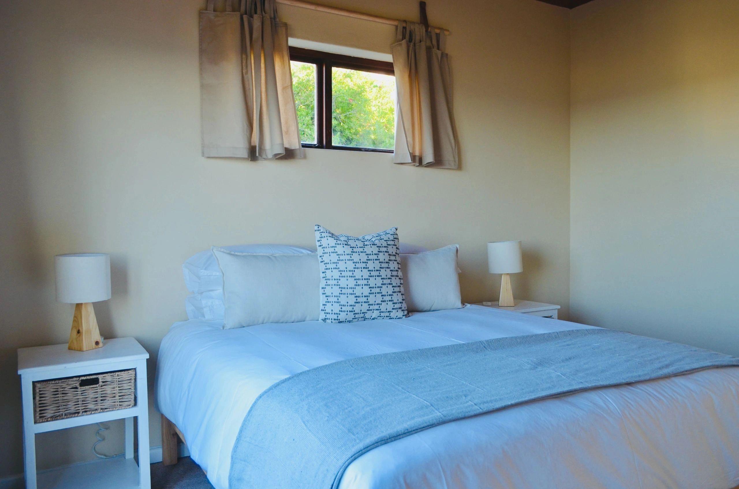 Cosy bedroom with a double bed, bedside lamps, and a window with garden view