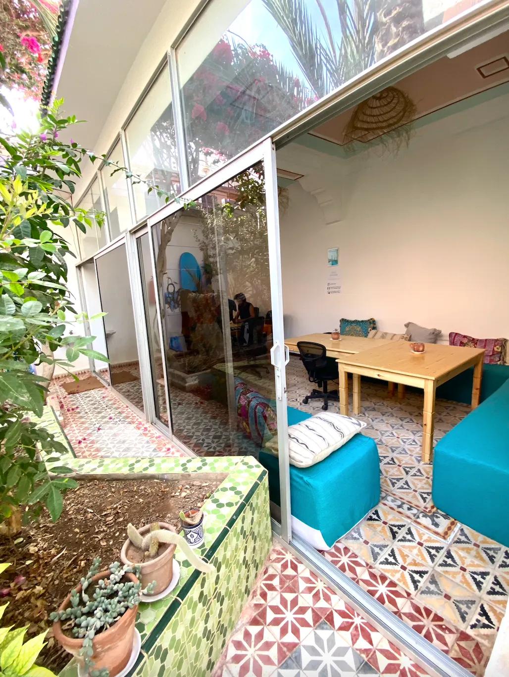 View from the garden into the coworking room through glass doors, with plants in the foreground