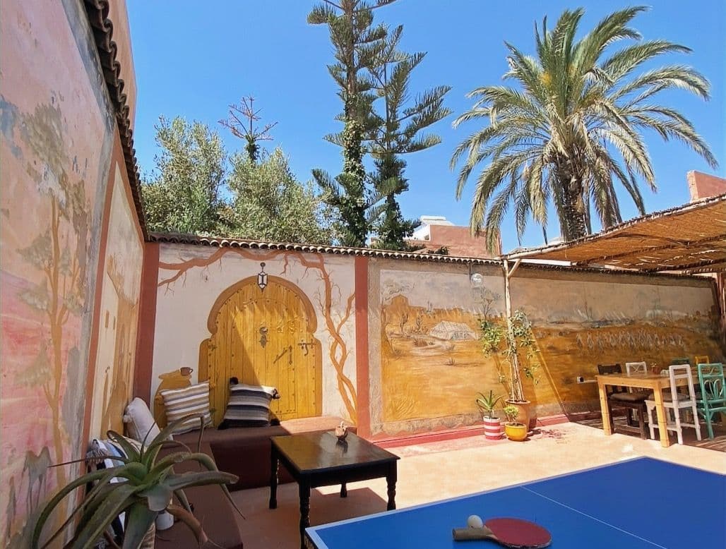 Outdoor terrace area with ping-pong table, Moroccan murals, and palm trees