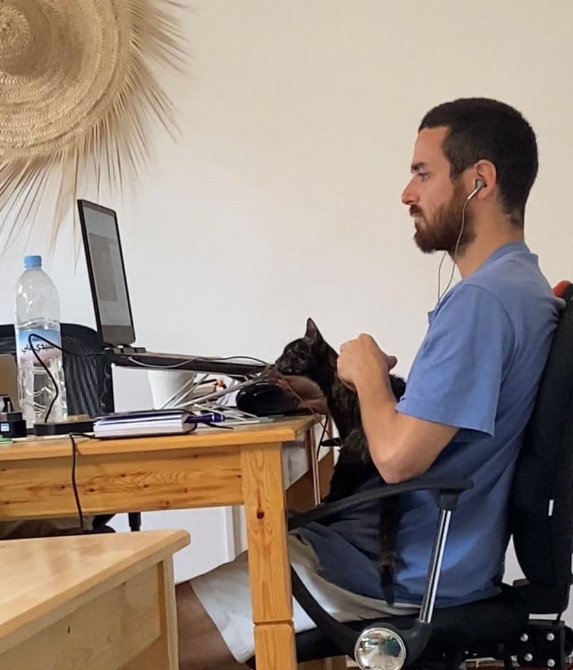 Person working at a laptop in the coworking space with a cat on the desk
