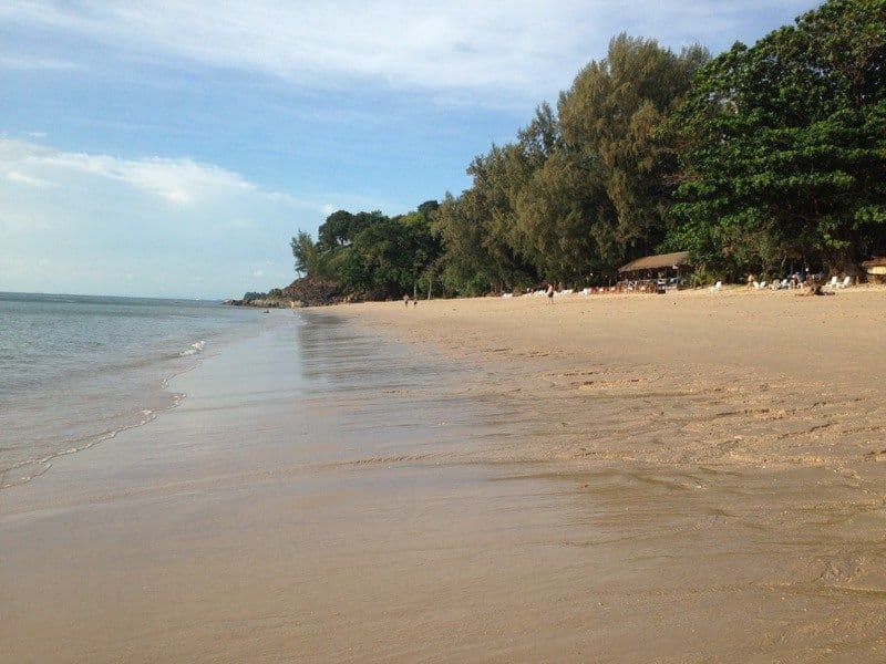 Long sandy beach at Koh Lanta with calm sea and tropical trees