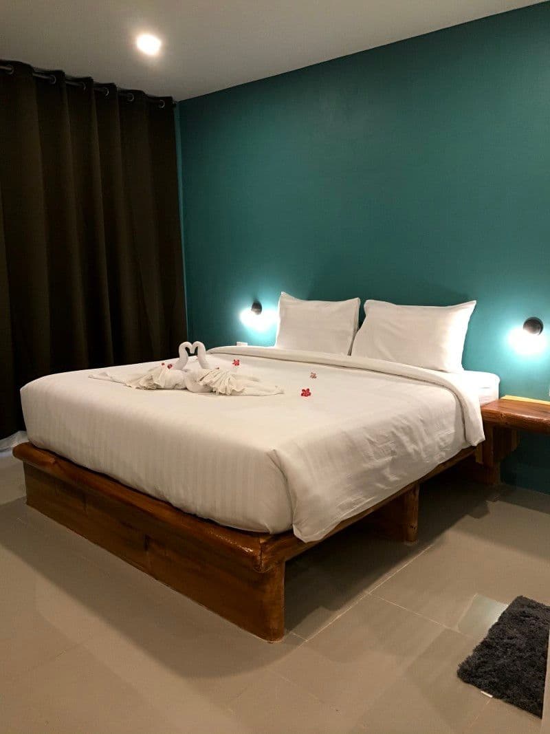 King-size bed with white linen on a wooden frame in the private garden bungalow