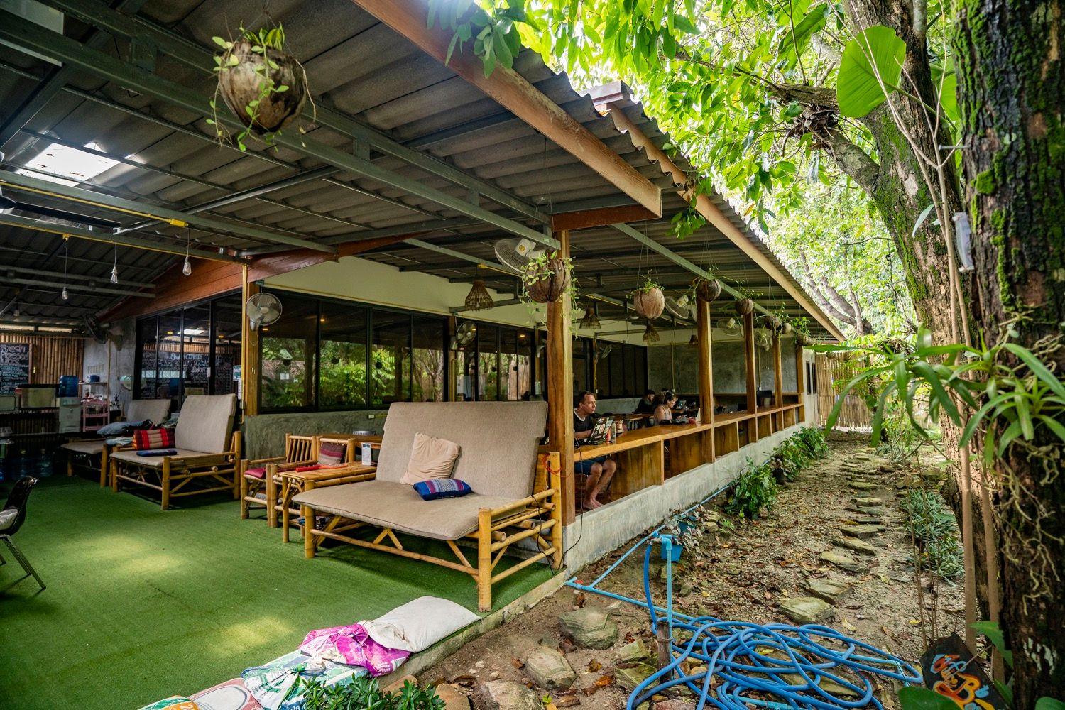 Open-air deck area with lounge furniture, bamboo chairs, and lush tropical garden surroundings