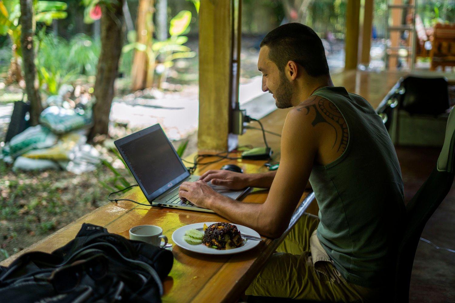 Member working on a laptop with food at the outdoor deck bar counter