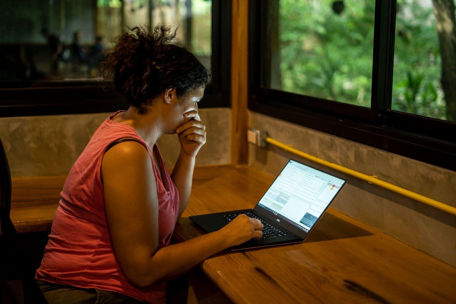 Member working on a laptop in a quiet focus A/C room with garden window view
