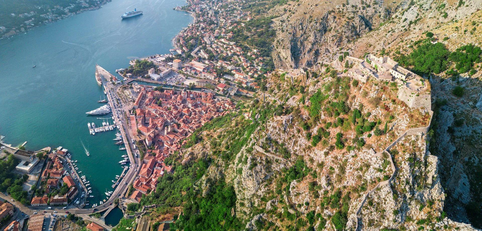 Aerial view of Kotor Old Town with the bay, marina, and fortress walls on the hillside