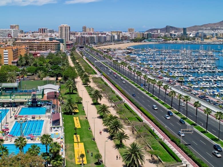 Aerial view of city with swimming pools, marina and coastal road