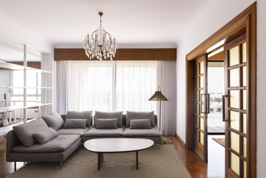 Living room with grey sofa, coffee table, chandelier and glass balcony doors