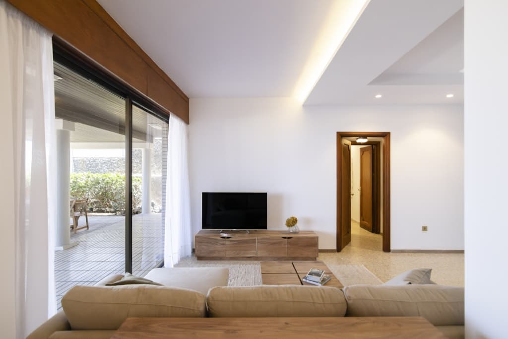 Living room with sofa, TV unit, and sliding doors opening to terrace with garden view