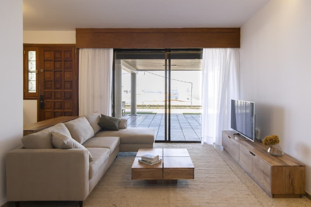 Living room with beige sofa, TV, wooden front door and terrace view