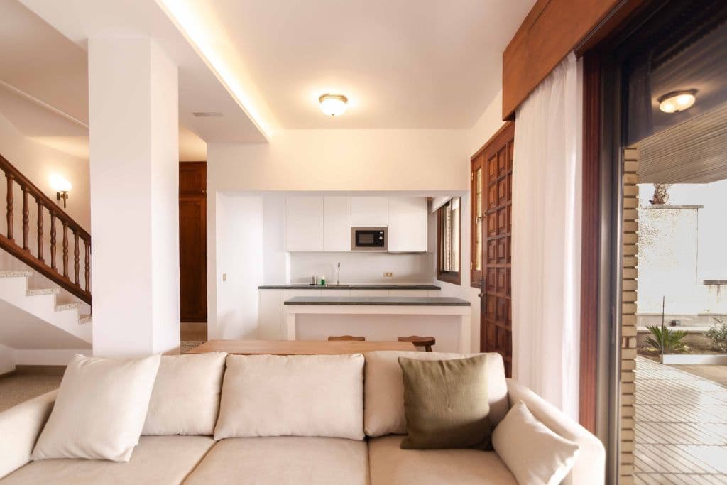 Open living area with sofa, staircase, kitchenette and view to terrace
