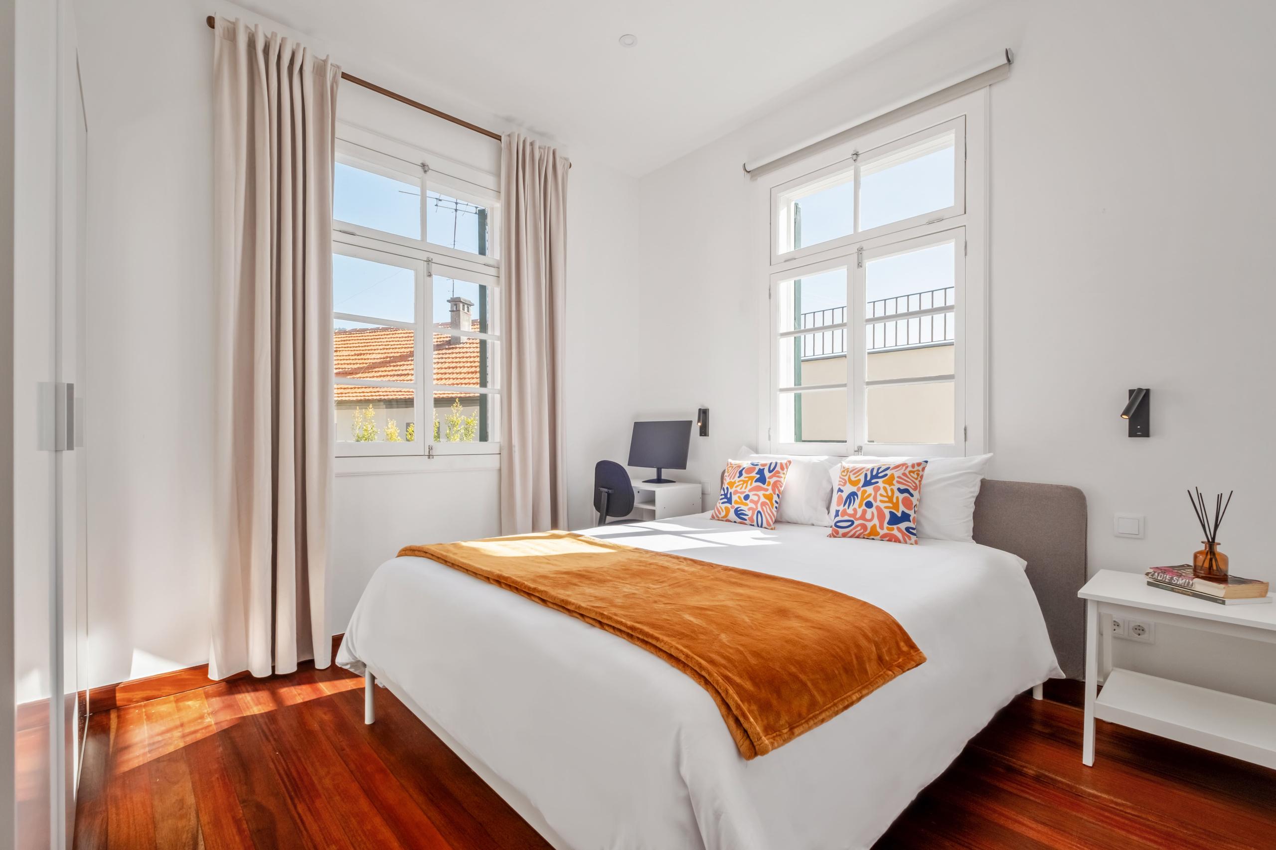 Buganvília room showing queen bed with orange bedding, colorful cushions, and wall decor