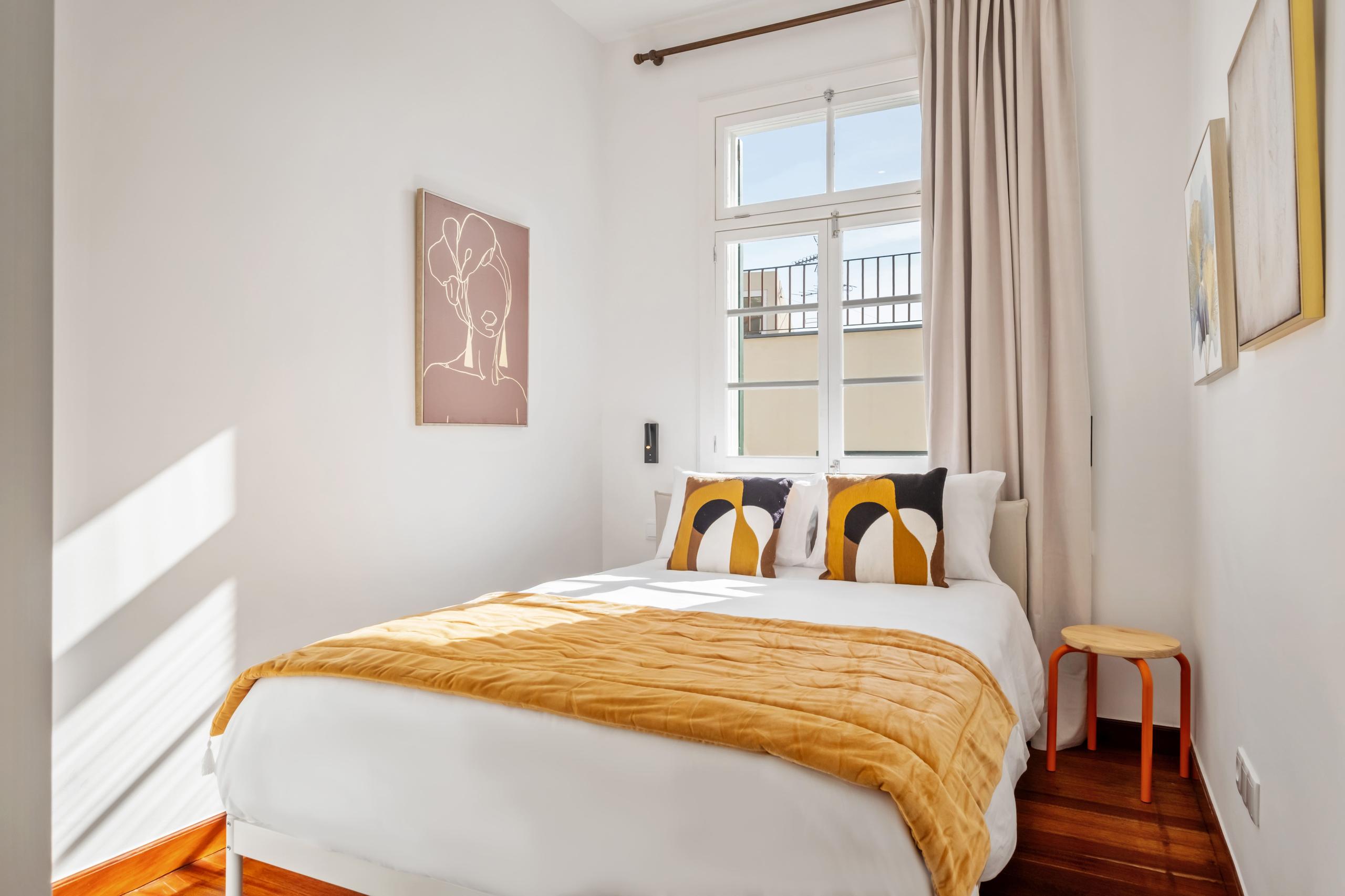 Orquídea room showing double bed with yellow bedding, artwork, and window with curtains