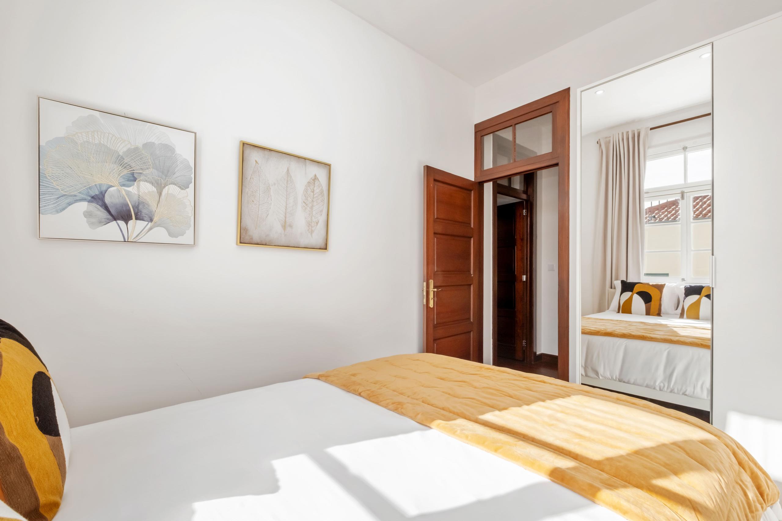 Orquídea room wide angle showing double bed, artwork, mirror, and wooden door