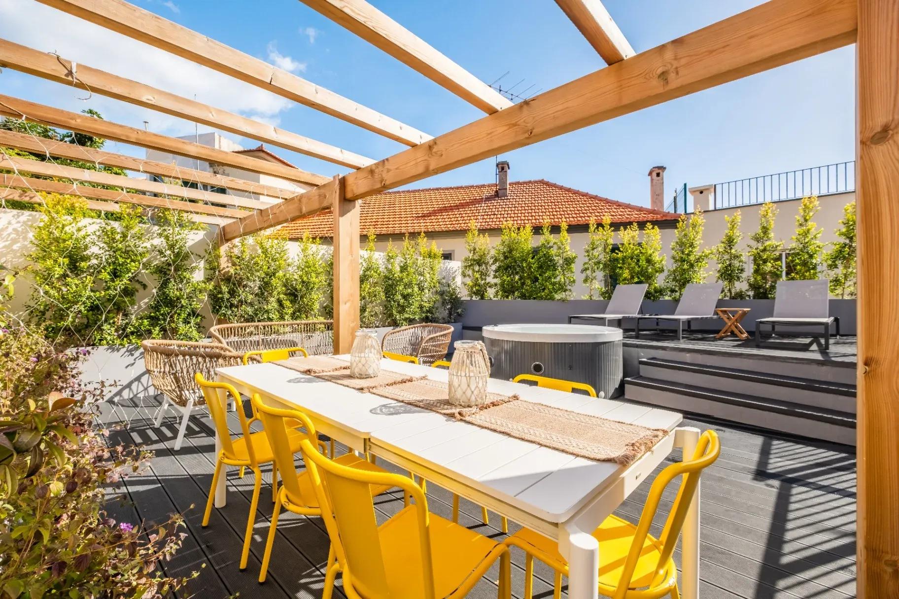 Outdoor courtyard terrace with jacuzzi, pergola, yellow dining chairs, and lounge area