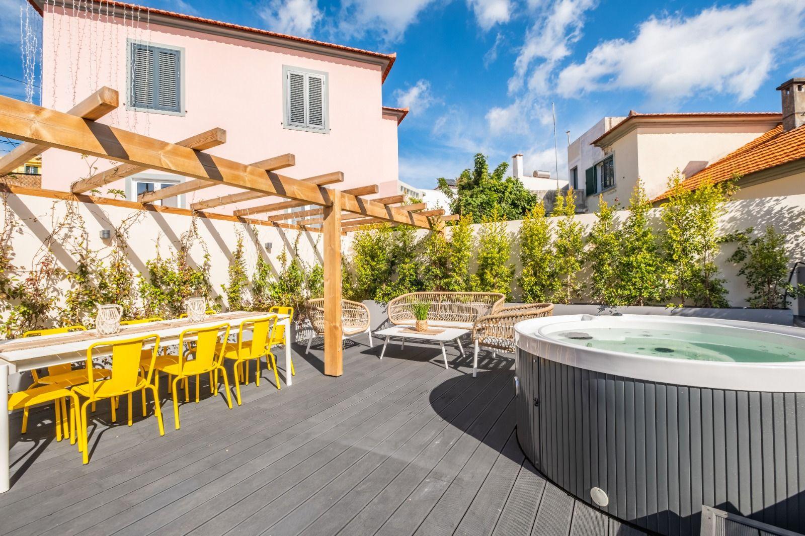 Outdoor terrace with jacuzzi, pergola, yellow dining table and chairs, and lounge seating