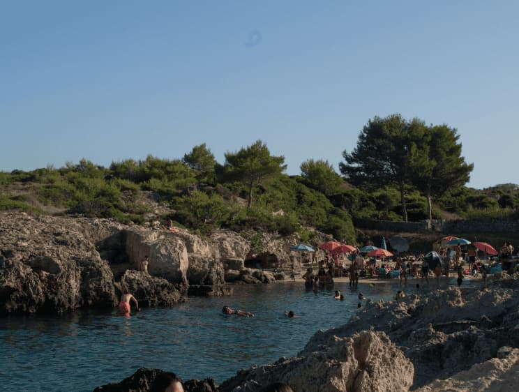 Rocky beach with umbrellas in Puglia near Masseria Olga coliving