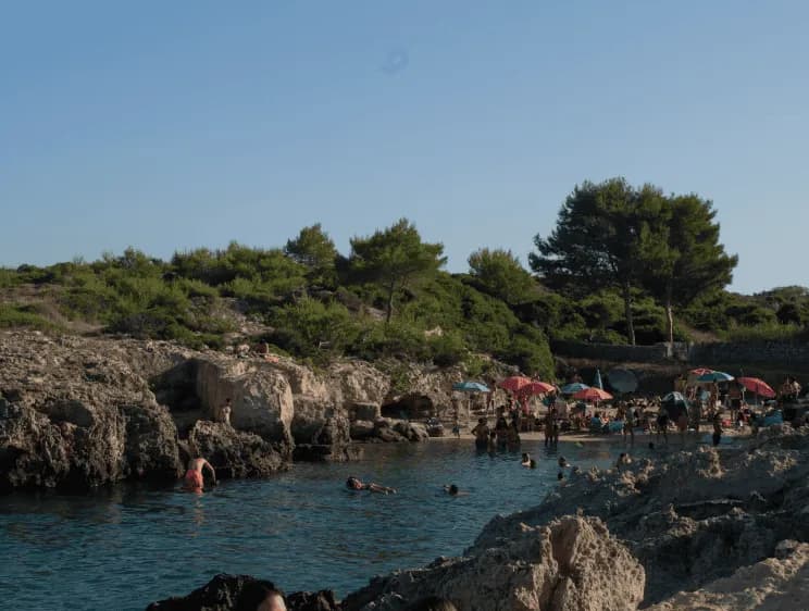 Rocky beach with umbrellas in Puglia near Masseria Olga coliving