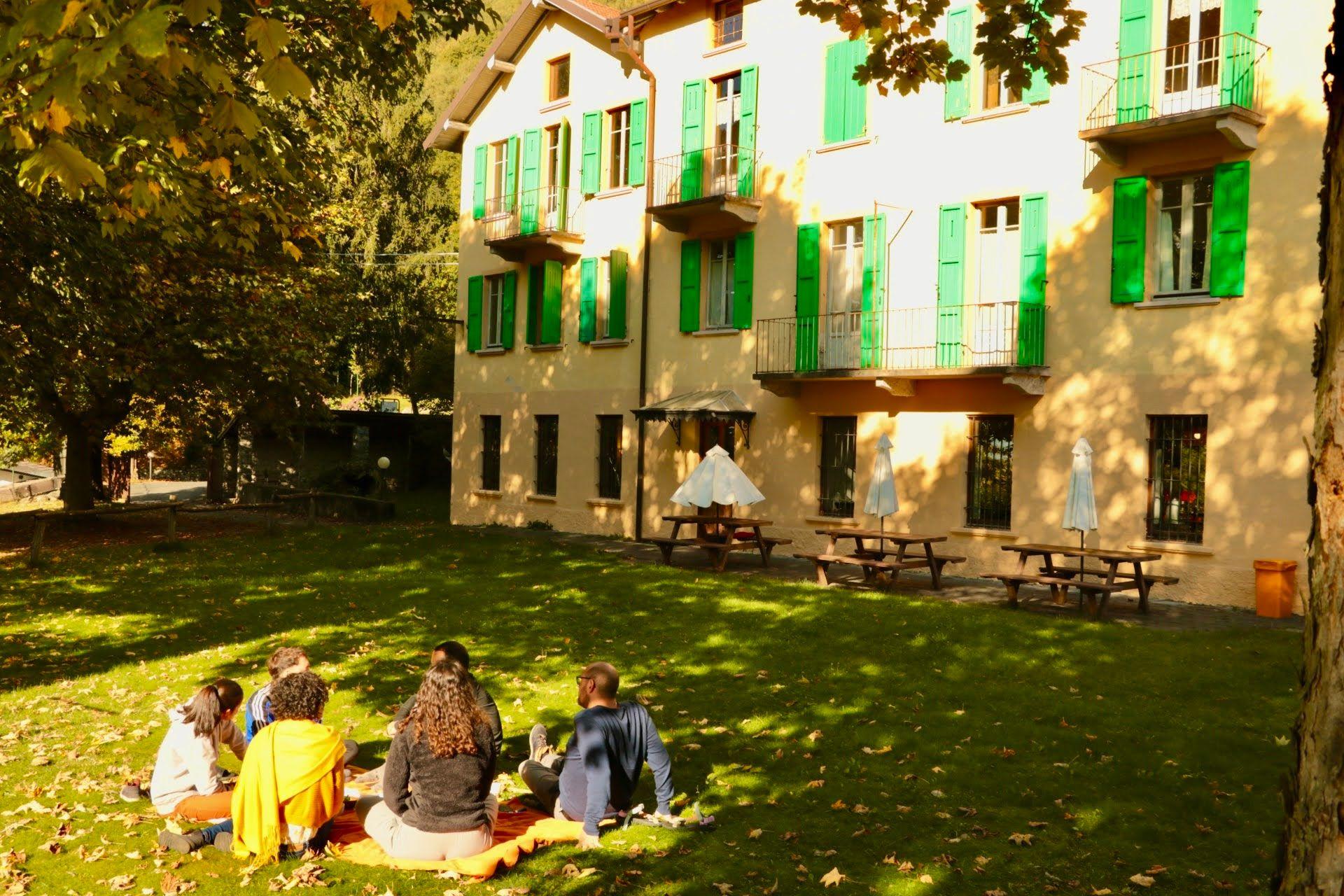 Group of residents sitting together on the lawn in autumn, with the Montino building facade visible in the background