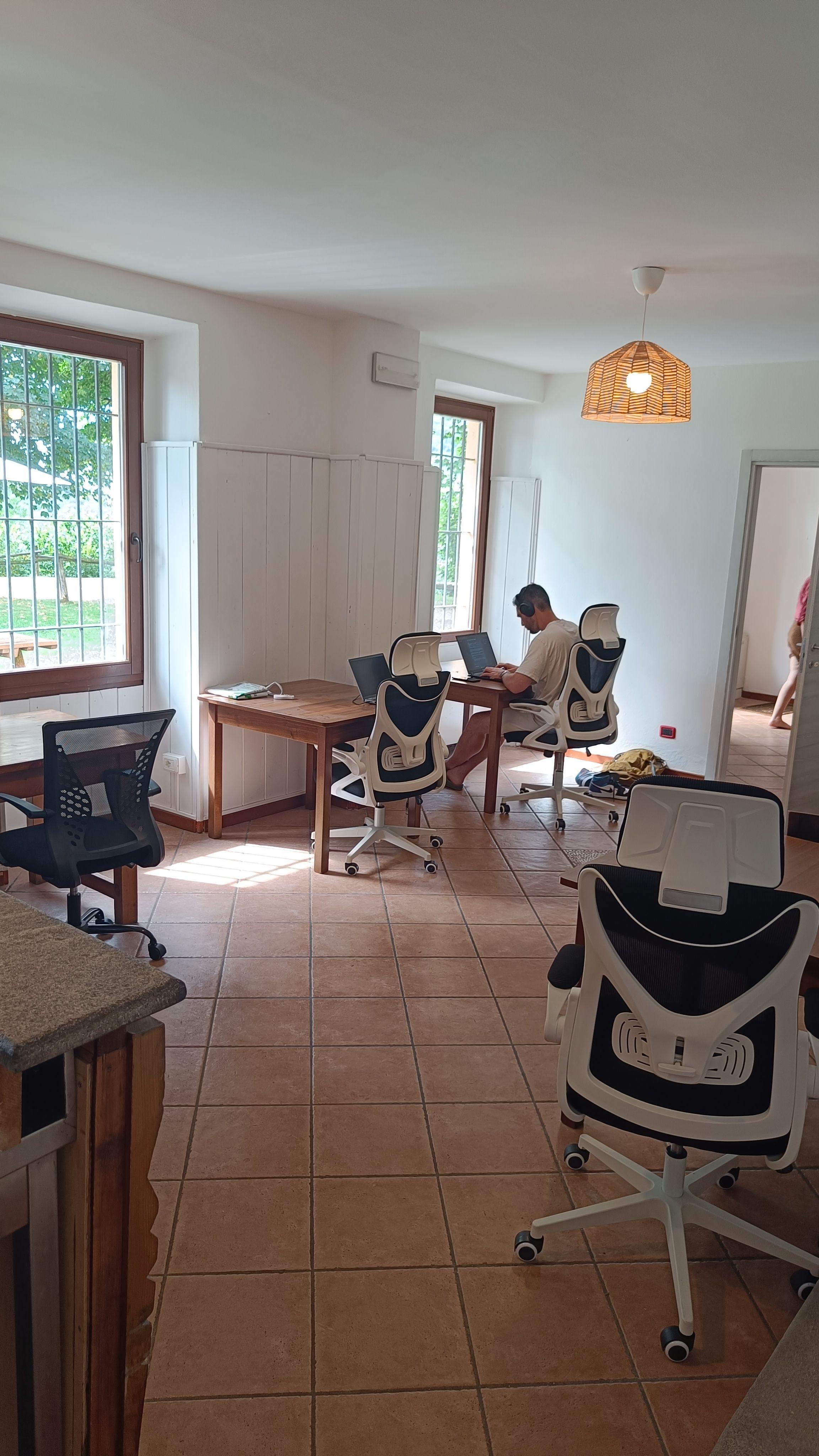 Resident working on a laptop in the coworking space with ergonomic chairs and natural light from windows