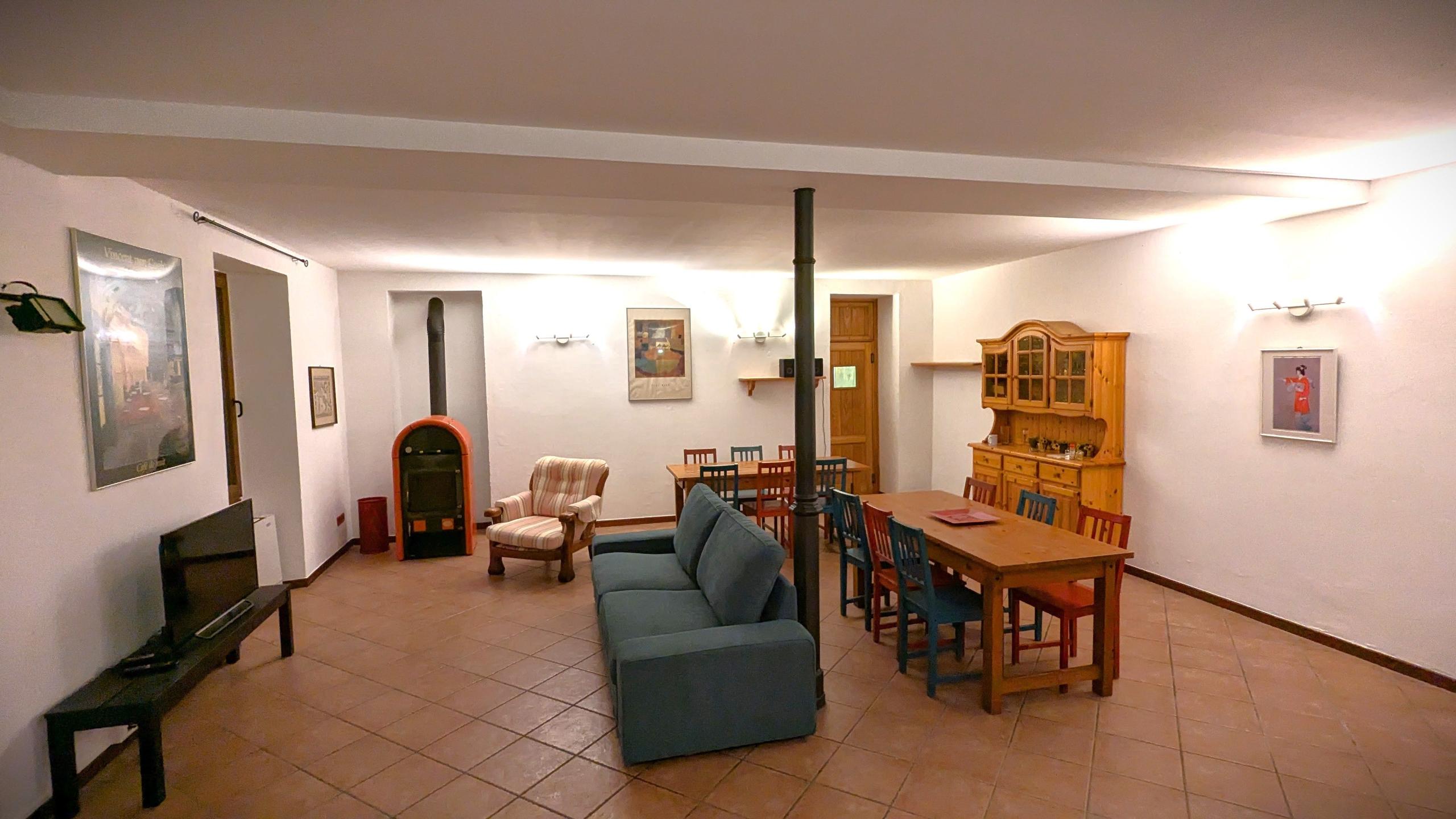 Common area with a sofa, dining table, chairs, wood-burning stove, and TV