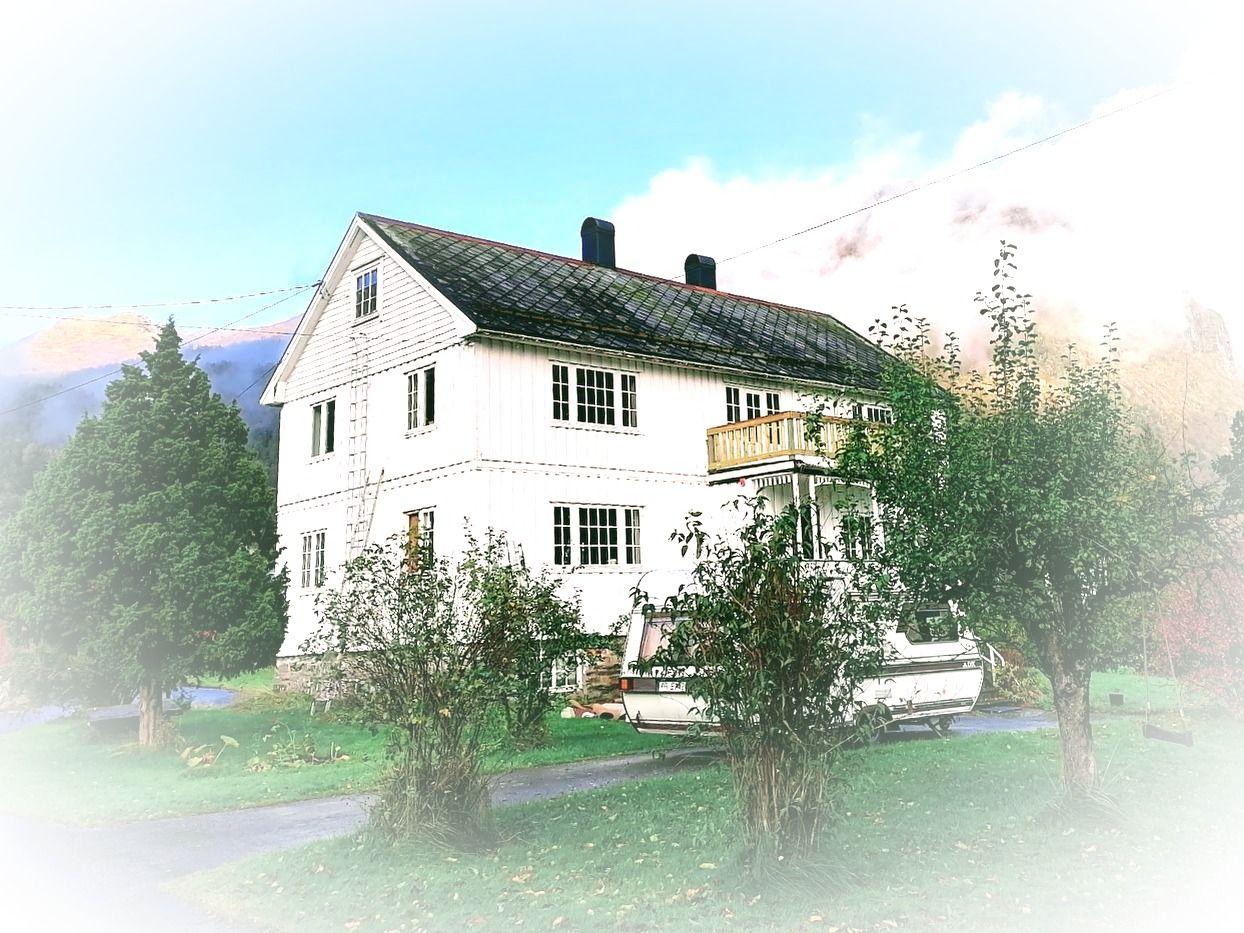 Exterior view of the Moritsgarden farmhouse, a white multi-storey building with a balcony, surrounded by trees and mountains