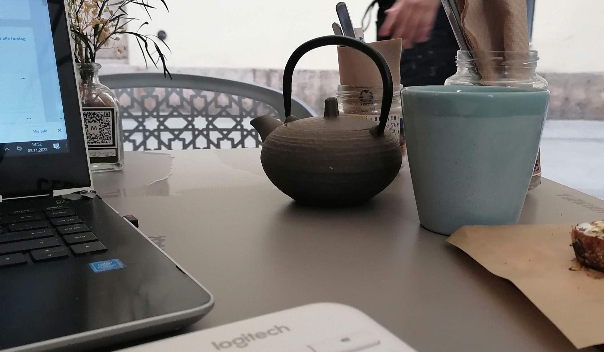 Interior of Moritsgarden showing a coworking/dining area with tables, chairs, and a laptop