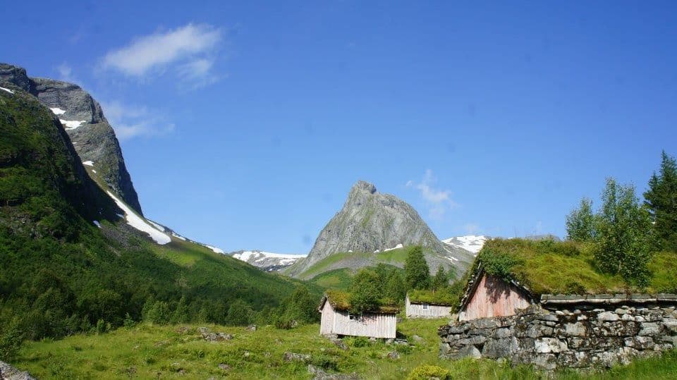 Traditional Norwegian mountain valley with old farm buildings and the pyramid-shaped mountain Keipen in the background