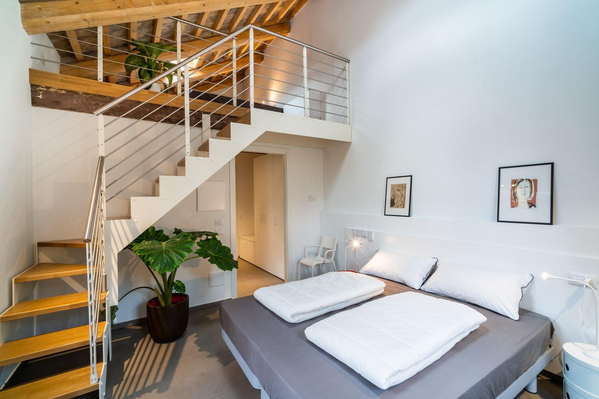 Private 4-bed loft room showing the lower double bed area with stairs leading to the loft level above