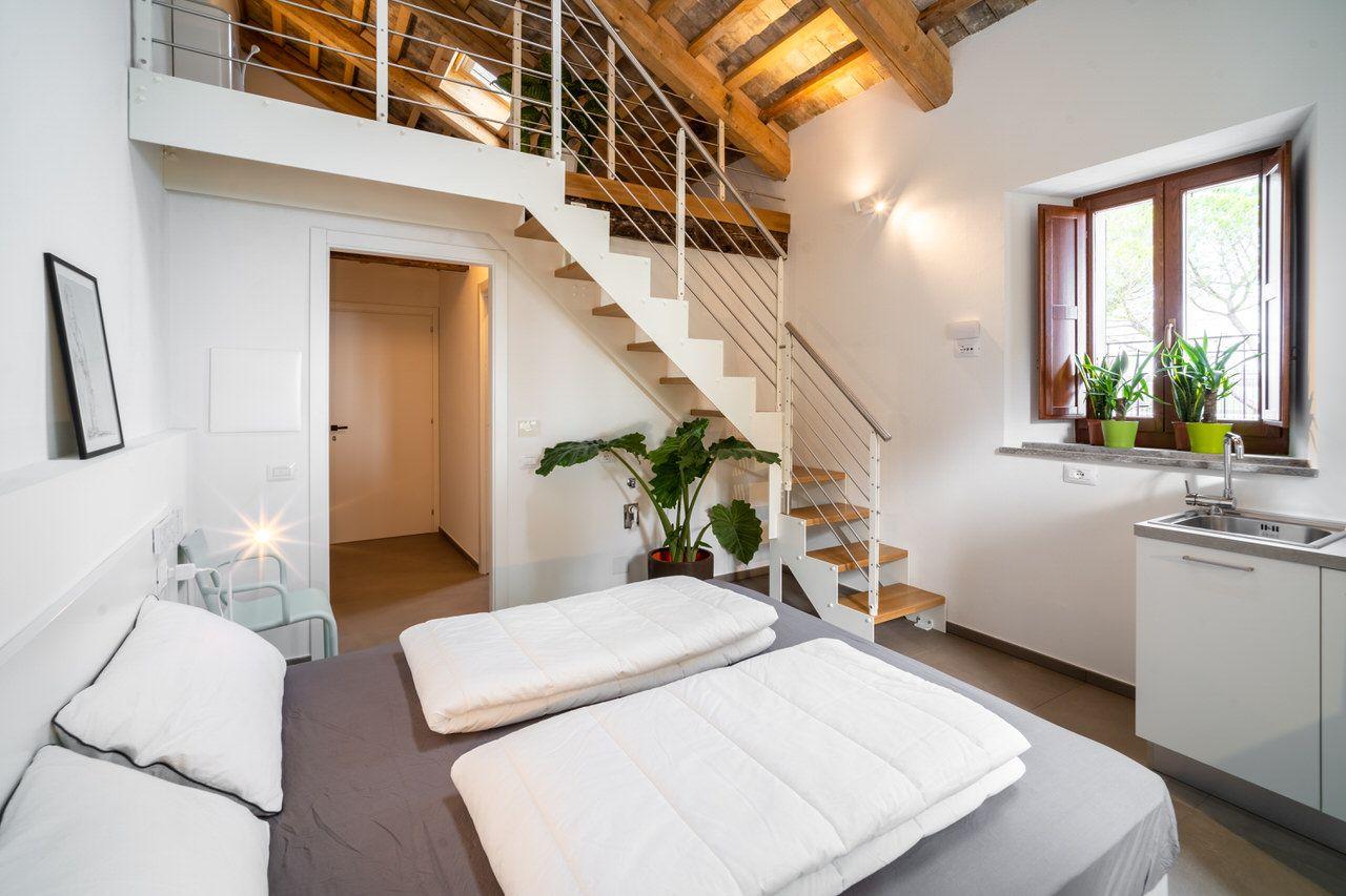 Private 4-bed loft room with double bed, loft level above, kitchenette with sink, and wooden beam ceiling