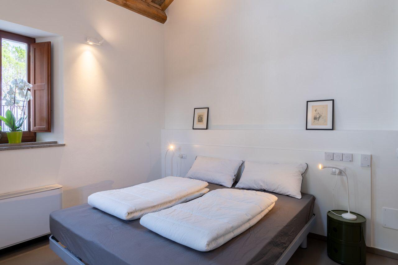 Private double bedroom with wooden beam ceiling, a small window, and artwork on the walls