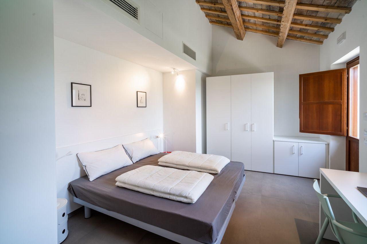 Private double bedroom with wooden beam ceiling, wardrobe, and desk area