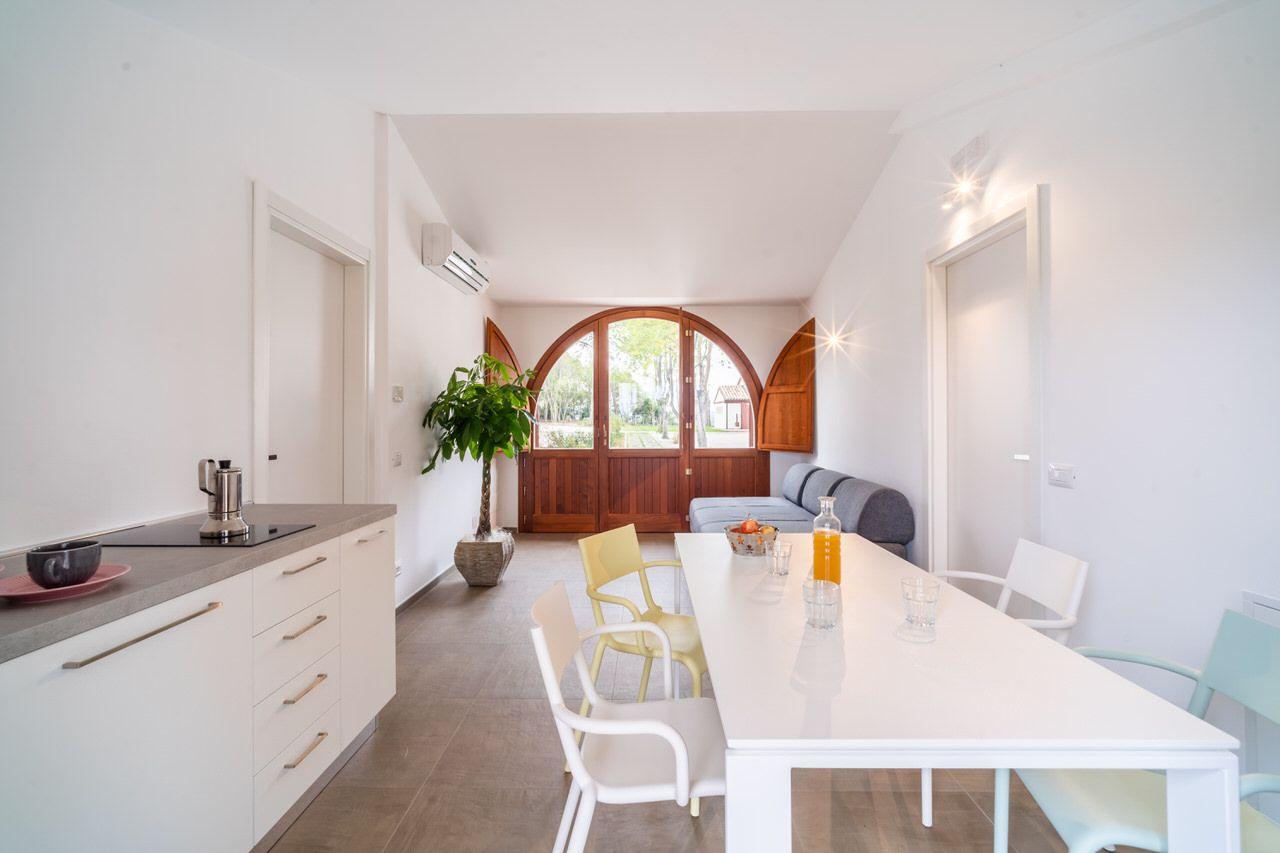 Mini apartment with open kitchen, dining table, sofa, and arched wooden entrance doors