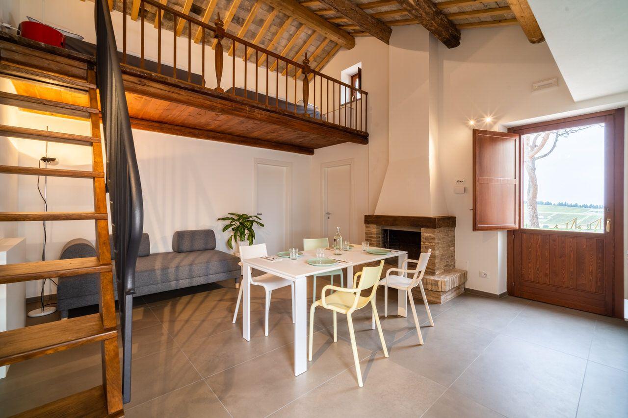 Private apartment living room with loft above, dining table, sofa, fireplace, and private entrance door