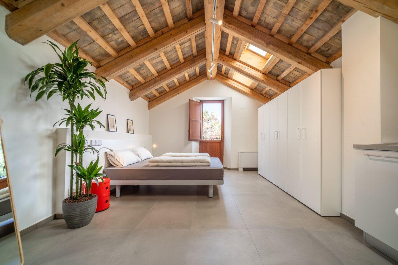 Spacious private double bedroom with wooden beam ceiling, skylight, wardrobe, and kitchenette area