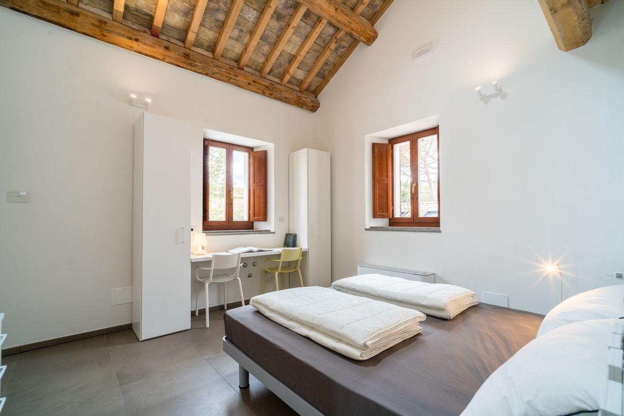 Private smart double room with wooden beam ceiling, two windows, a desk and wardrobe