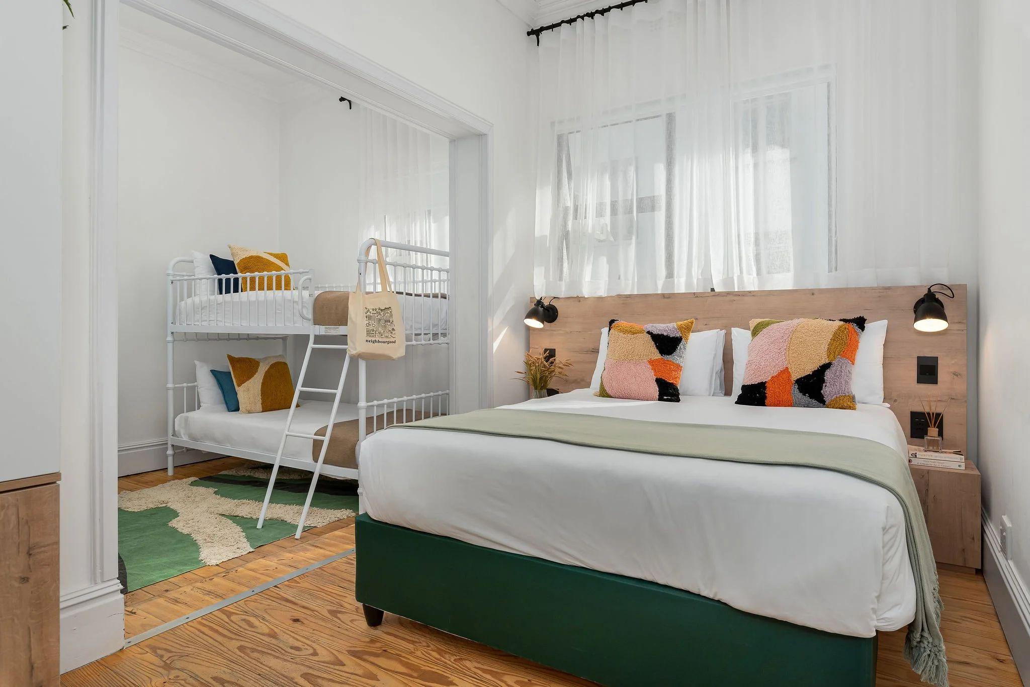 Family room at Neighbourgood Hill with queen-size bed and bunk bed, colourful cushions and children's rug