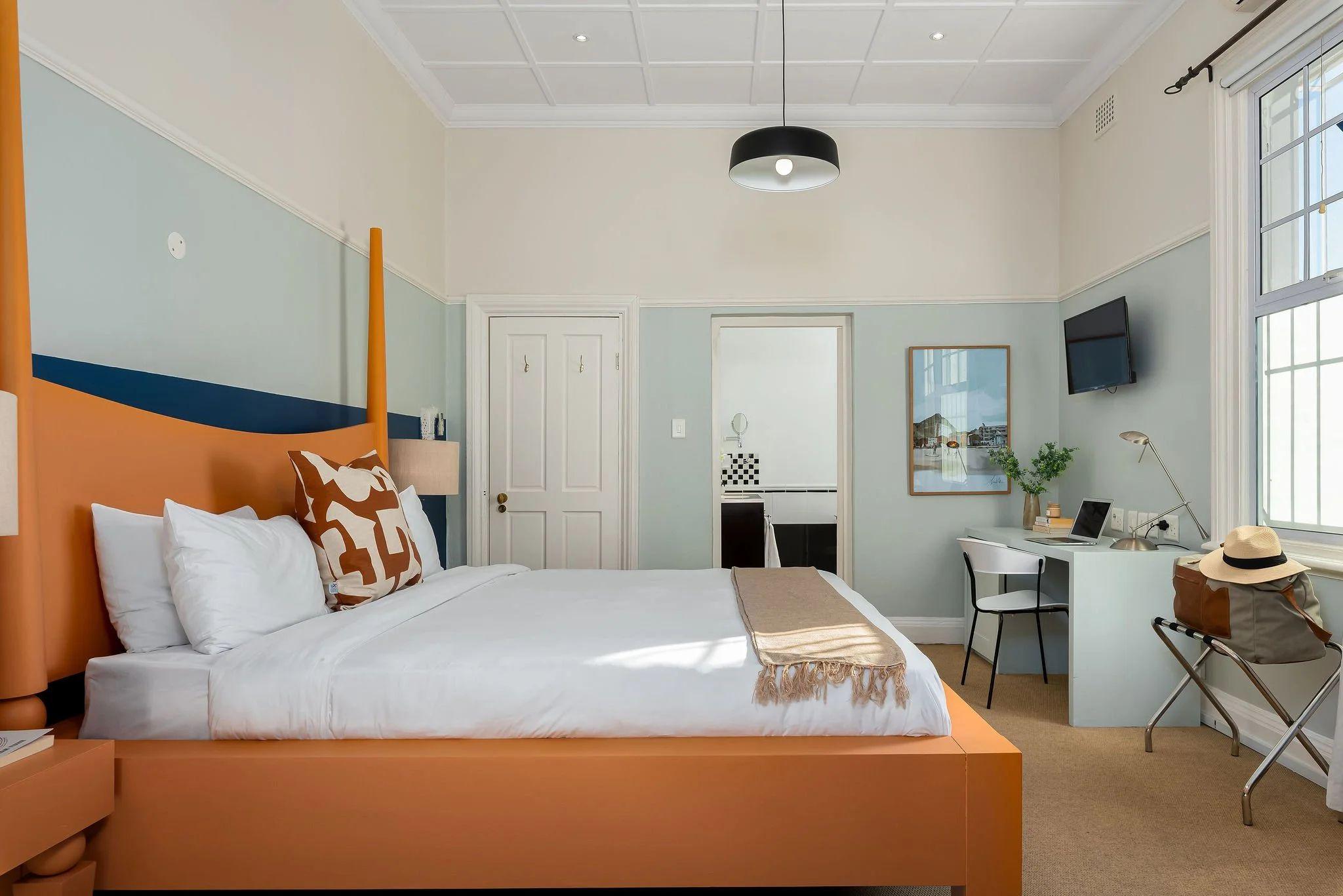 Spacious Hill Suites Superior room with king-sized orange bed, high ceilings, work desk, and en-suite bathroom visible