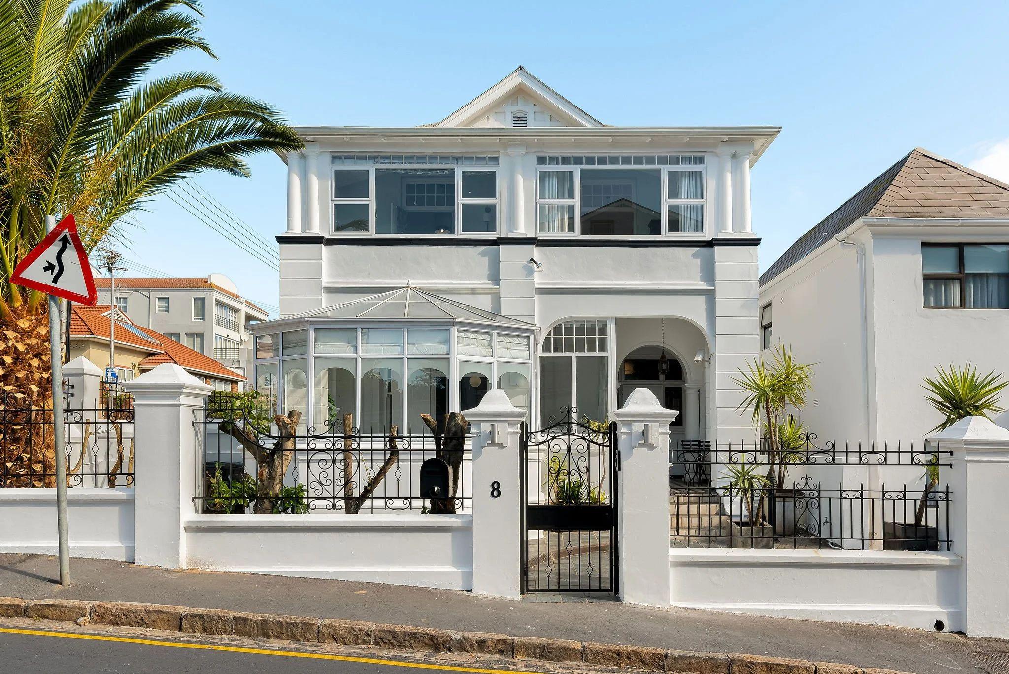 Street-level exterior view of Neighbourgood Hill building in Green Point, a white Victorian-style building with iron gate