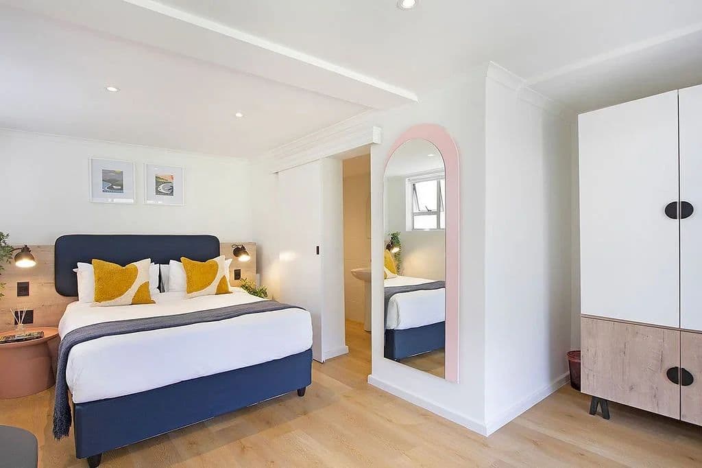 Deluxe room at Neighbourgood Hill with navy blue queen-size bed, full-length mirror, and wardrobe