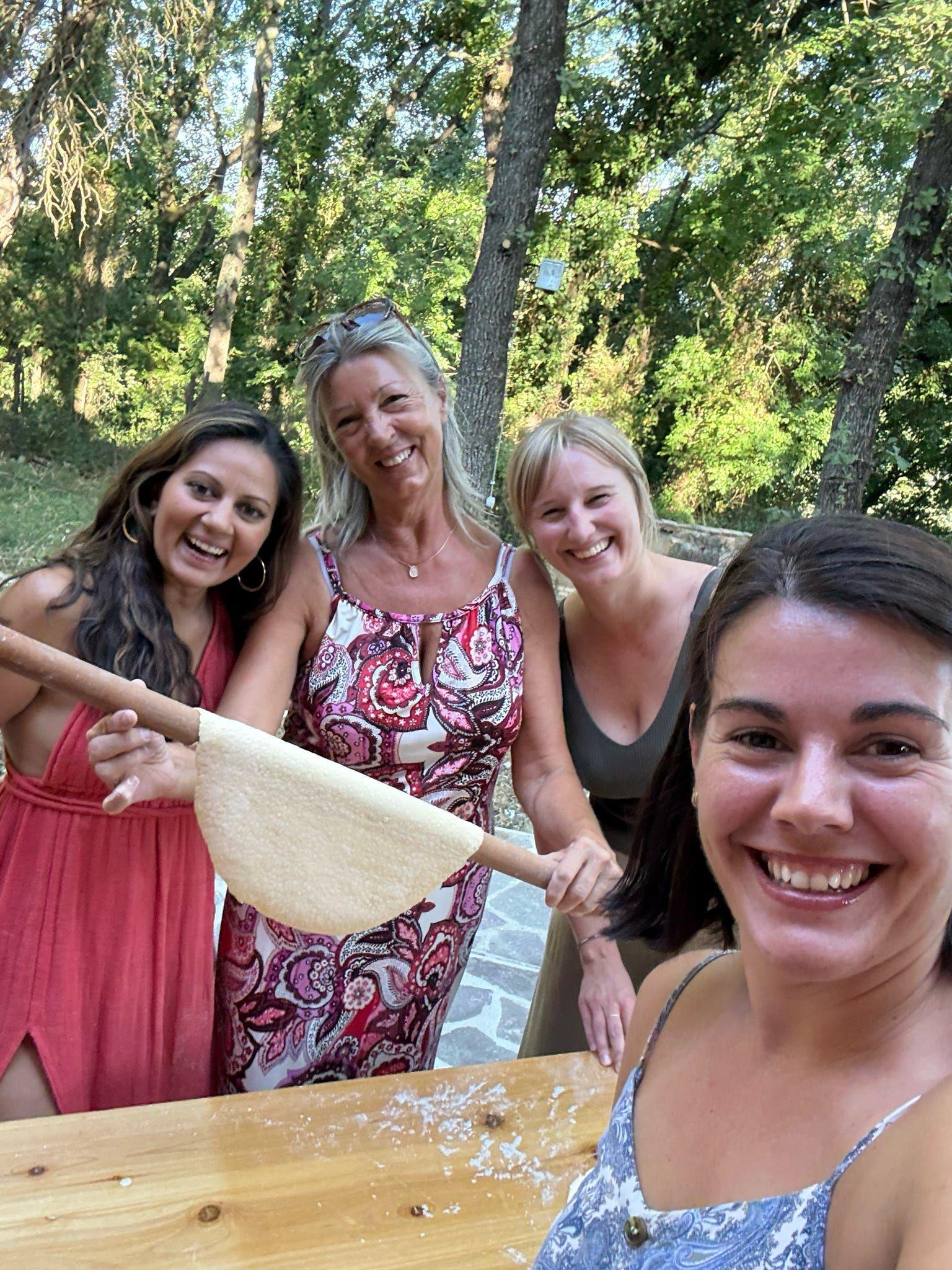 Multiple guests making pasta together in garden at coliving Italy for shared meal