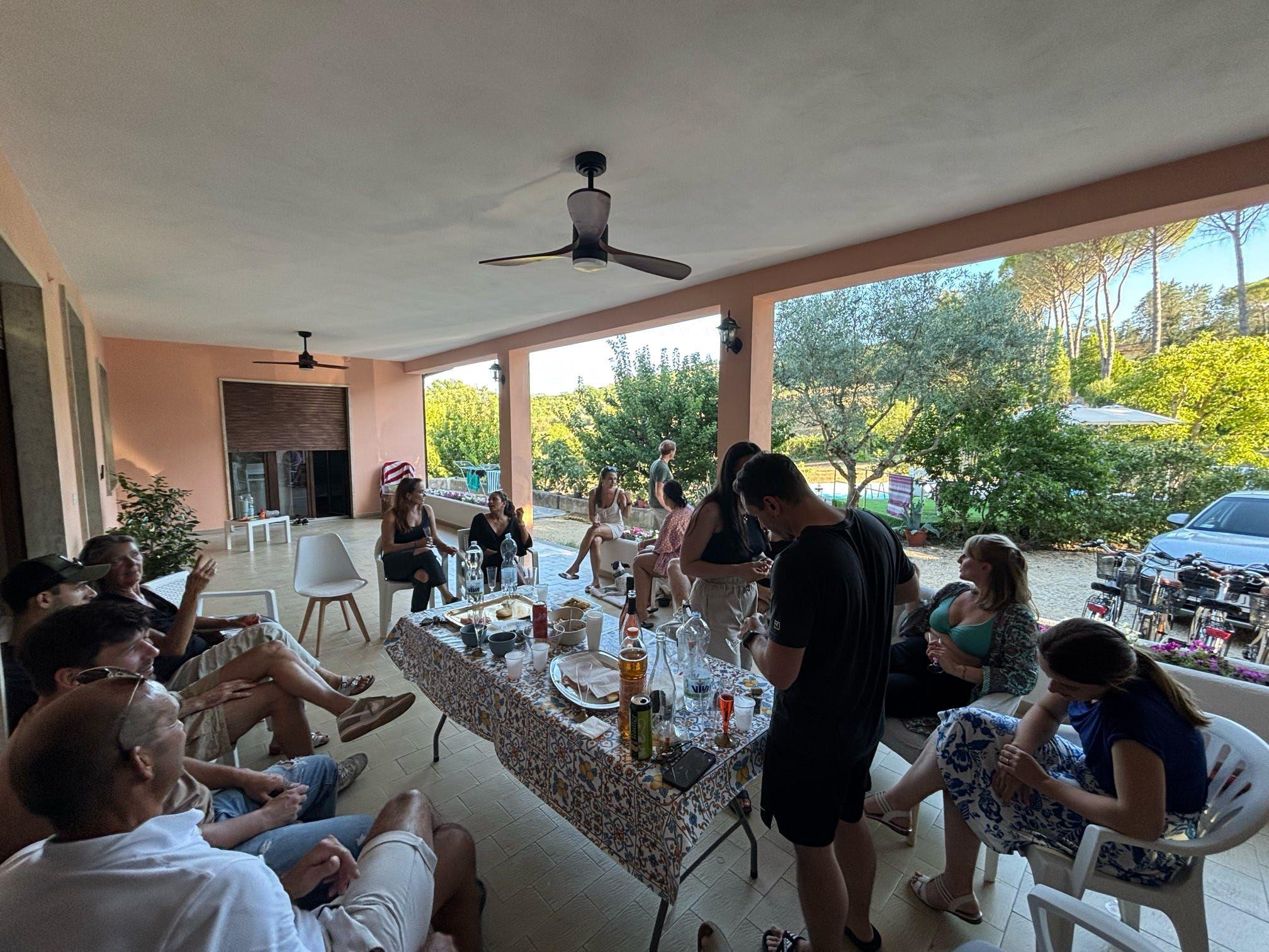 Group of digital nomads celebrating together at coliving in Italy toasting and having fun as community in the outside veranda