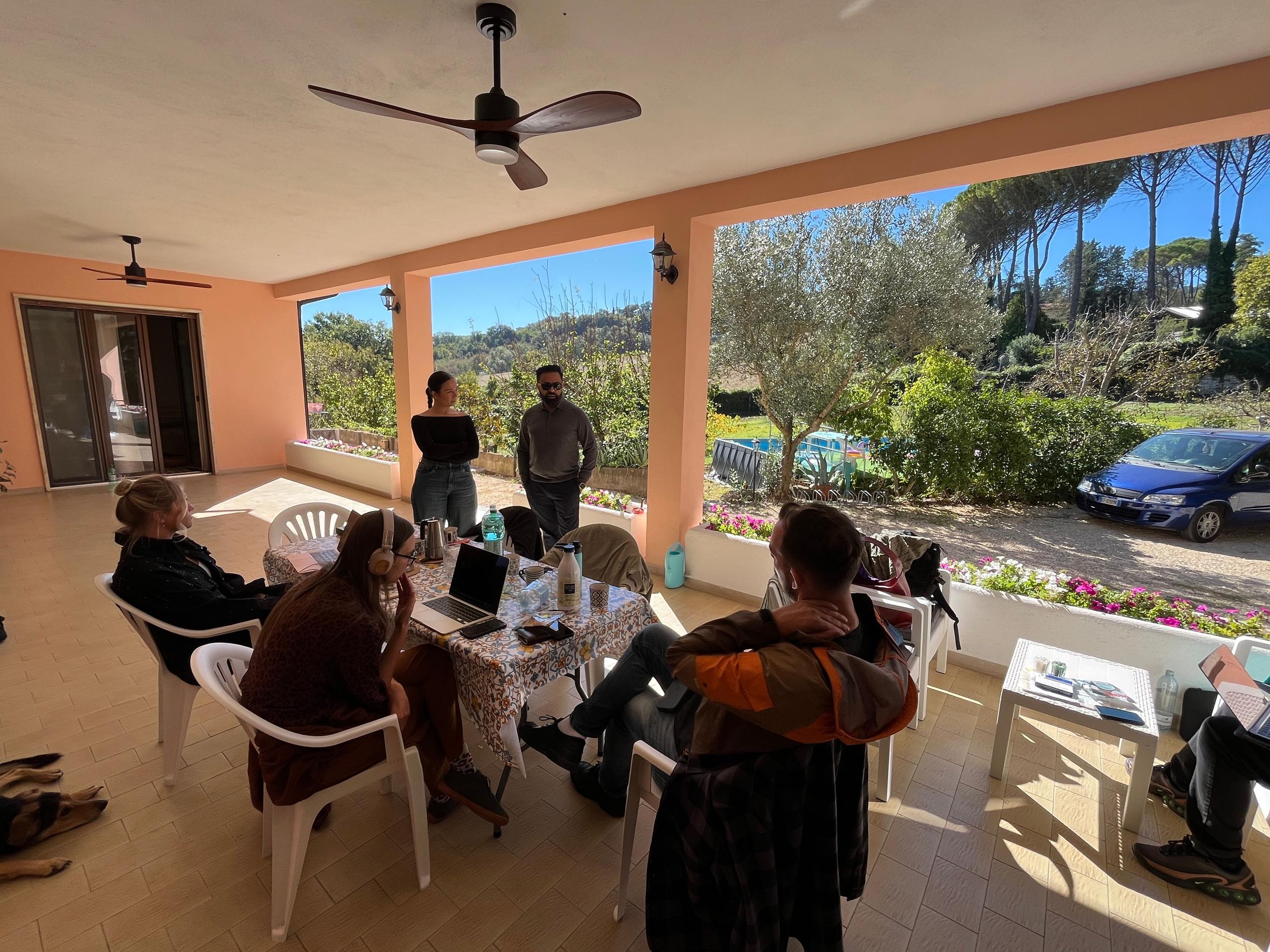People chatting and working on the main veranda at a coliving in Italy near Rome