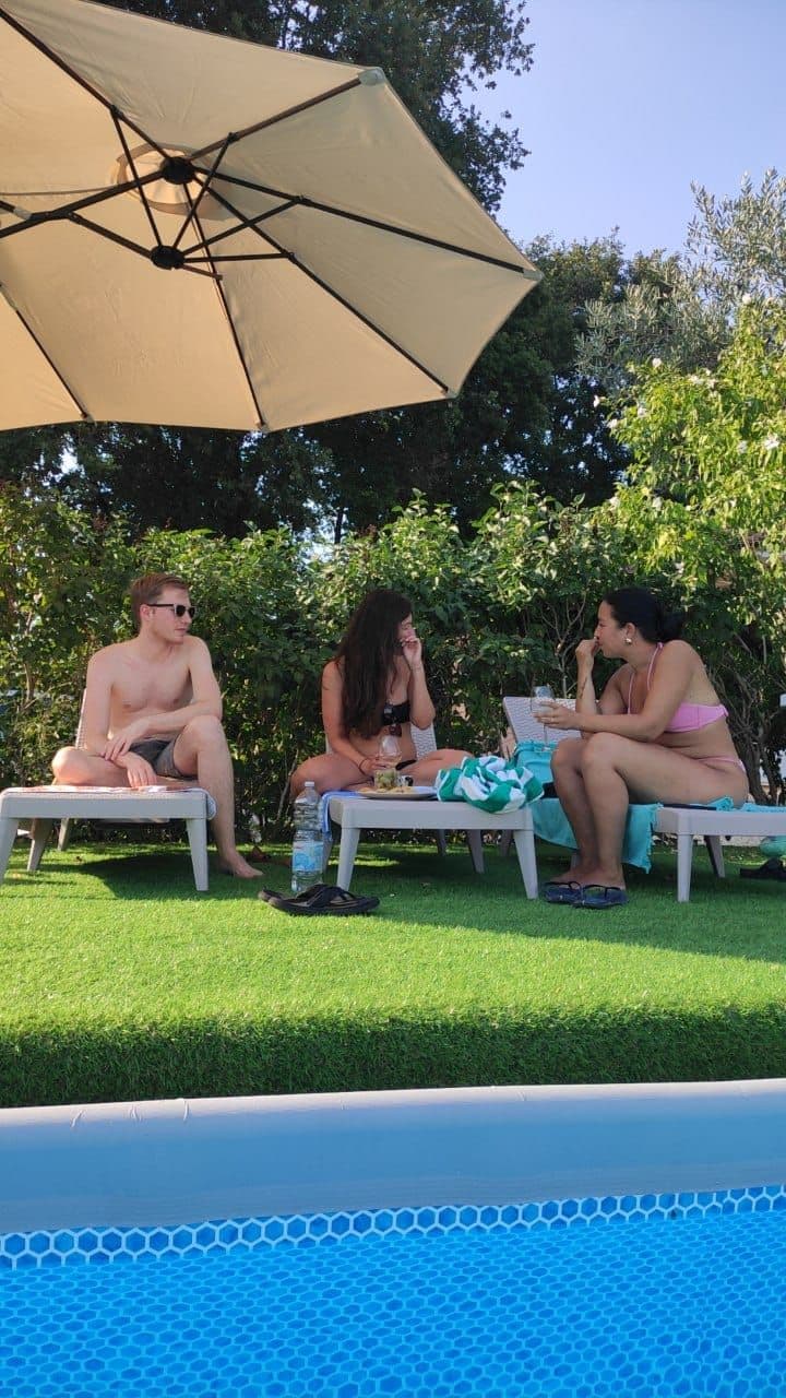 Guests relaxing on the pool patio at a coliving in Italy near Rome