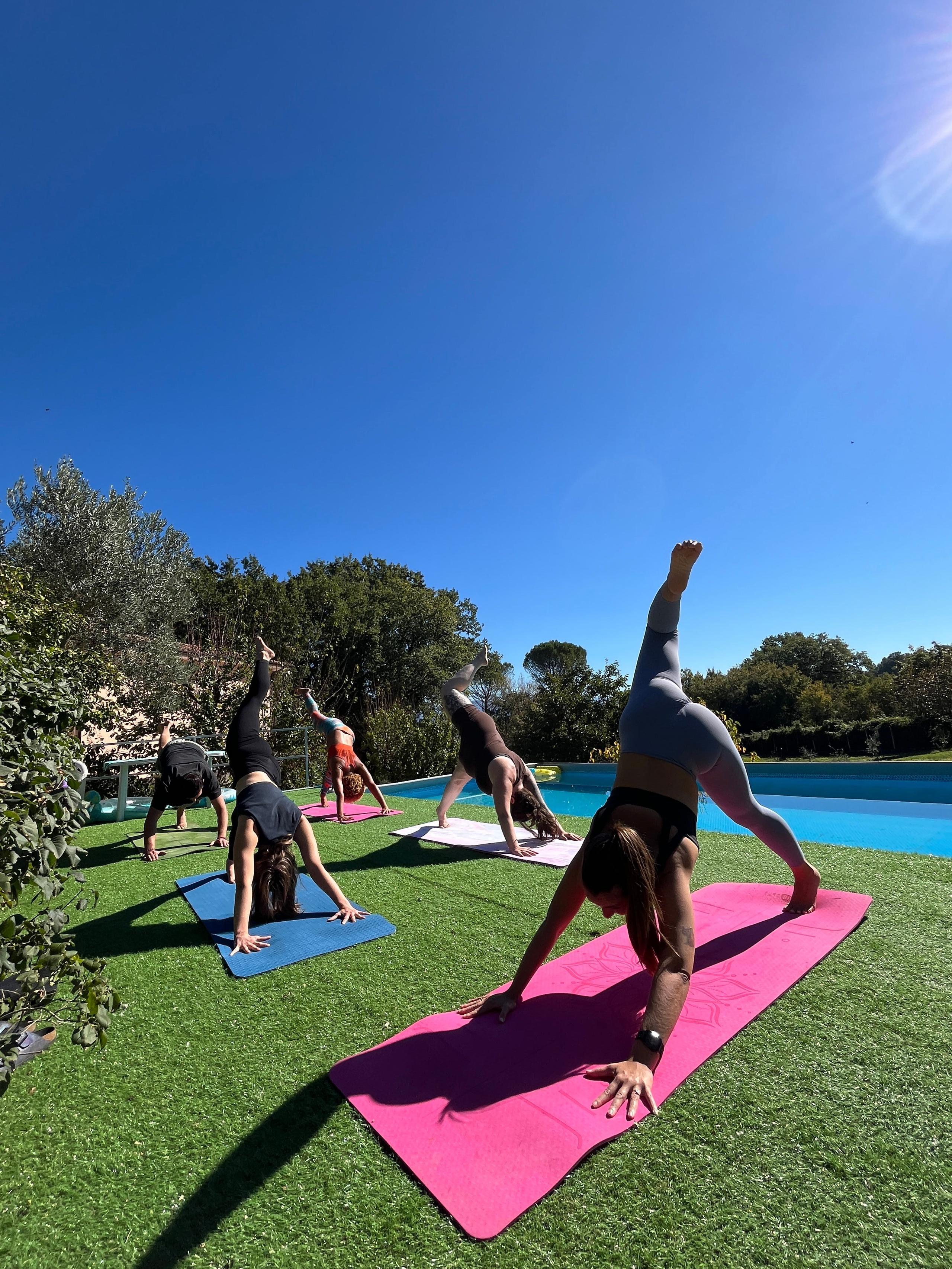 People doing yoga on the pool patio at a coliving in Italy near Rome with the pool in the background