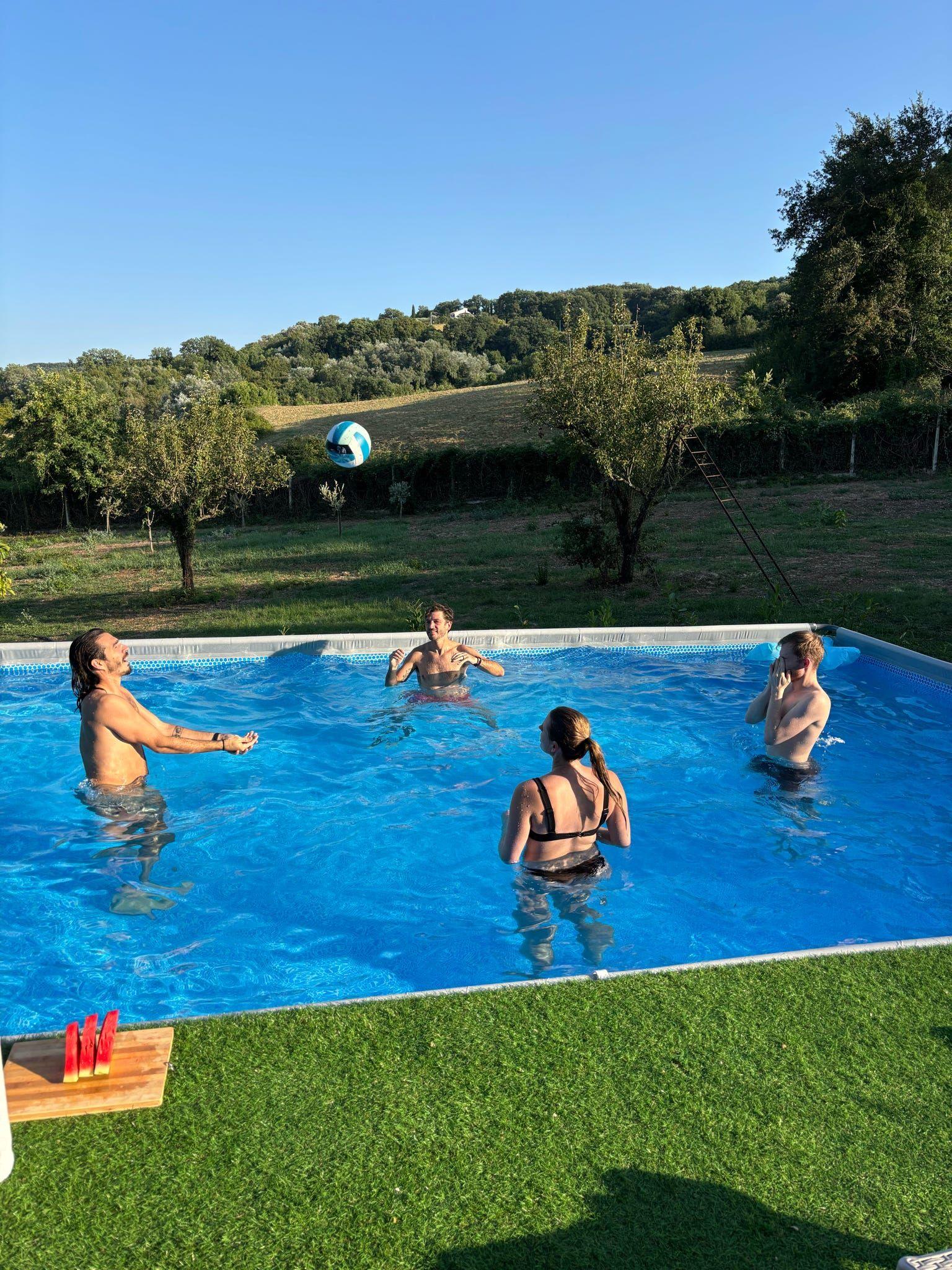 People playing volleyball in the swimming pool at a coliving in Italy near Rome