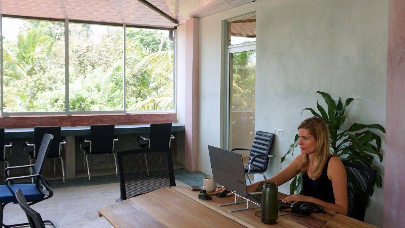Helene working at a desk in the coworking space at NETS Cowork and Colive, immersed in a focused and productive environment.