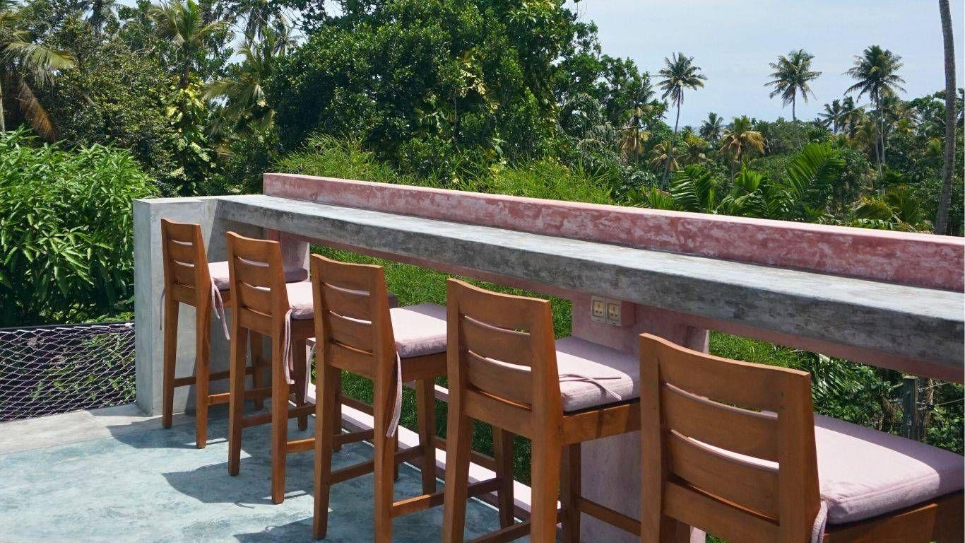 The high-top coworking outdoor area at NETS Cowork and Colive, featuring elevated workspaces with views of the surrounding greenery and natural light.