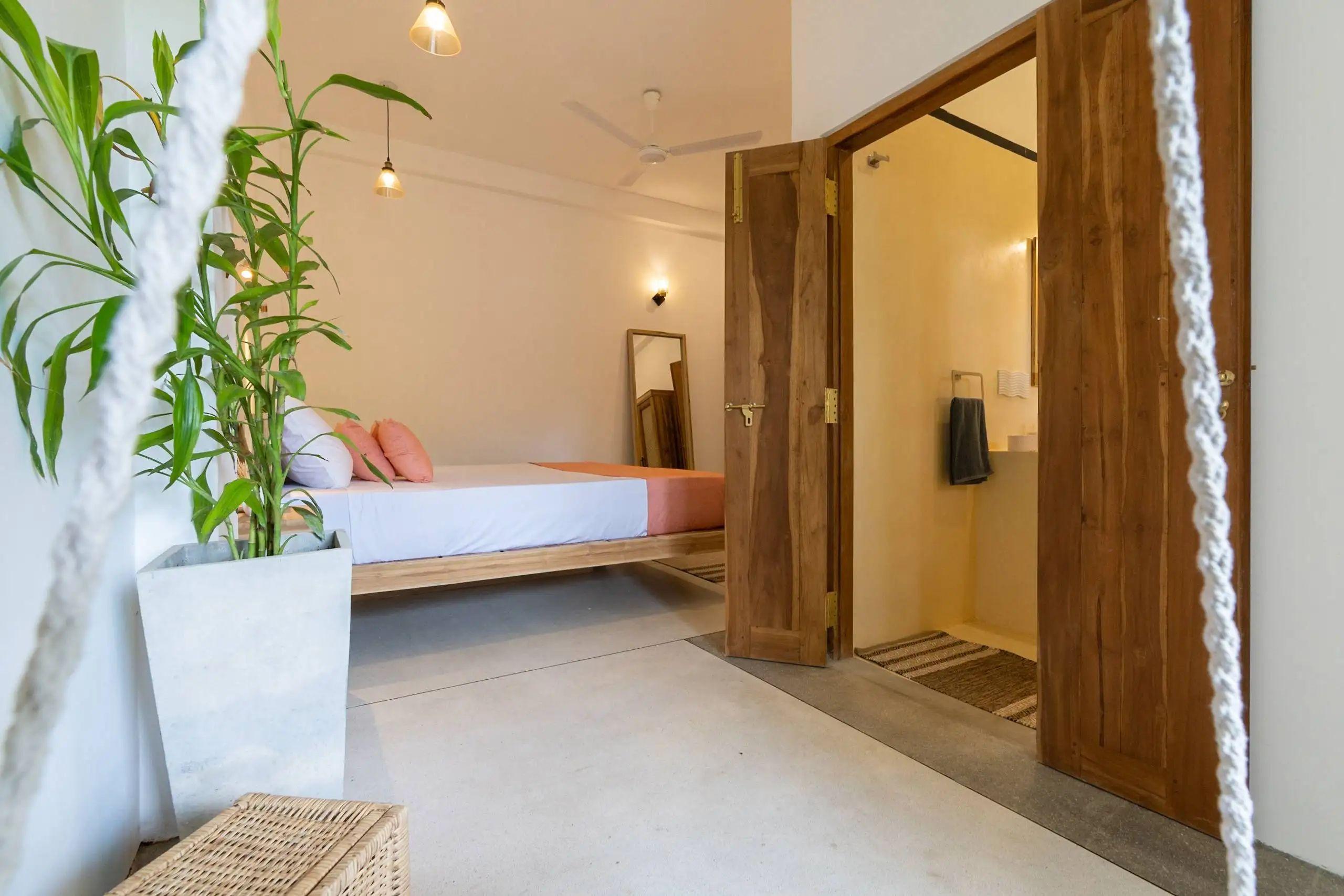 View of the Chic Suite from near the swing, showcasing the bed and the bathroom at NETS Cowork and Colive.