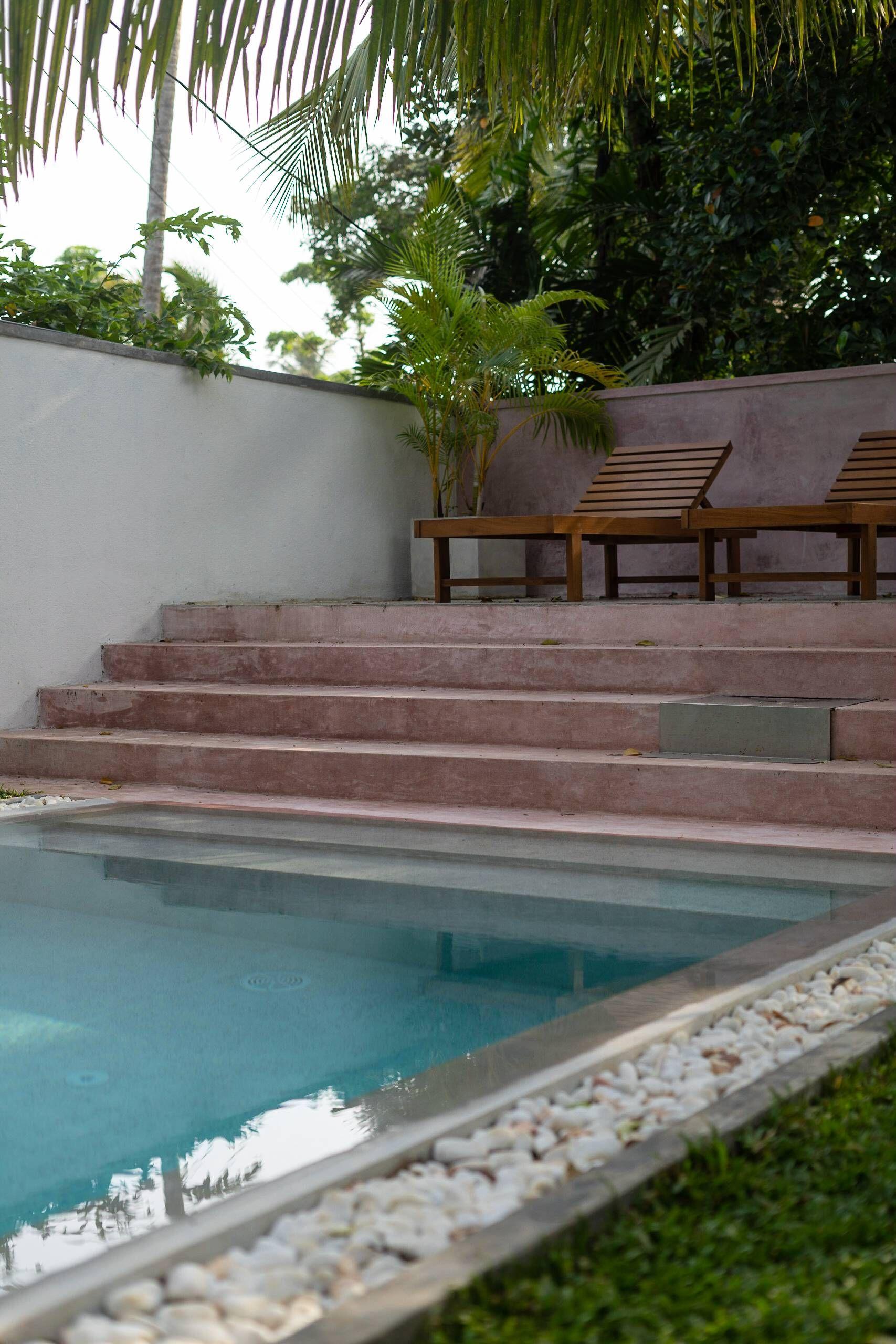 Swimming pool at NETS Cowork and Colive with comfortable sunbeds arranged around it.